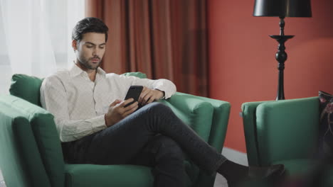 Business-man-scrolling-mobile-at-luxury-hotel.-Businessman-reading-phone