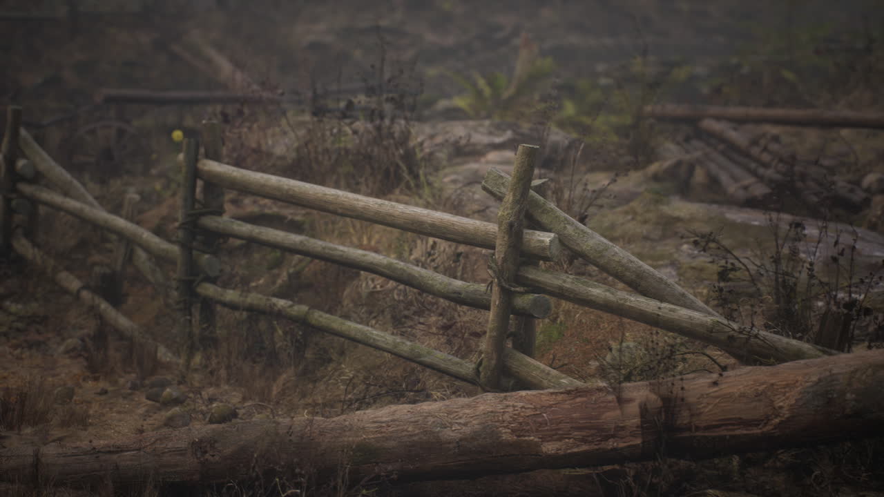 una vieja valla de madera con un campo de campo detrás de ella