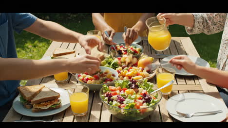 people enjoying an outdoor summer meal with salads and sandwiches