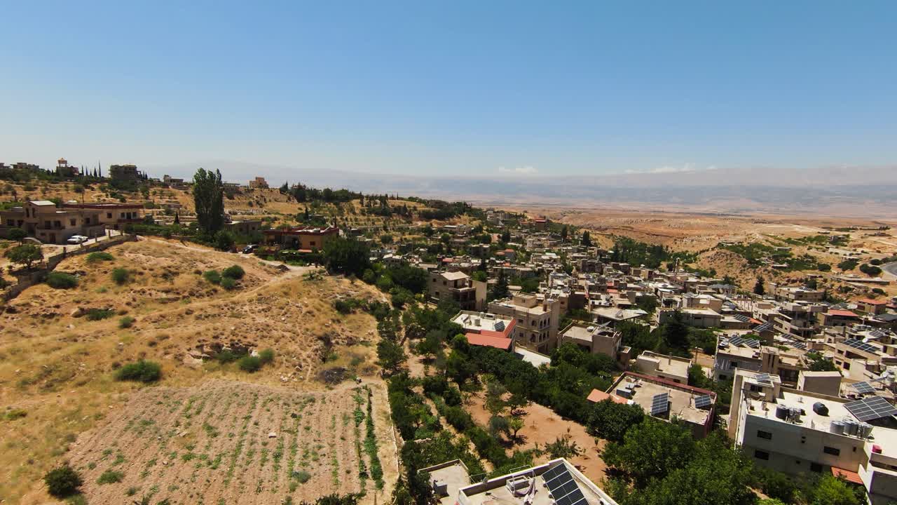 sobrevuelo aéreo ciudad libanesa rodeada de desierto durante el día soleado y cielo azul - paisaje montañoso con casas y plantas