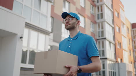 A-delivery-man-carries-a-package-to-customers-in-a-residential-area.-Grocery-delivery-and-online-shopping