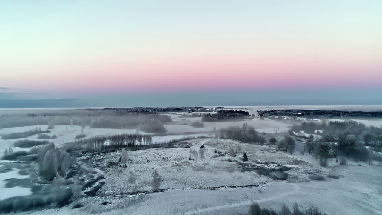 Frostige landwirtschaftliche Felder mit Bäumen und leuchtendem Himmel, Luftaufnahme.