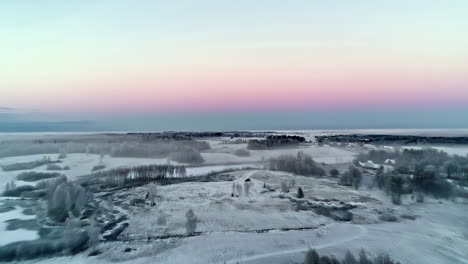 Frosty-agriculture-fields-with-trees-and-glowing-sky,-aerial-view