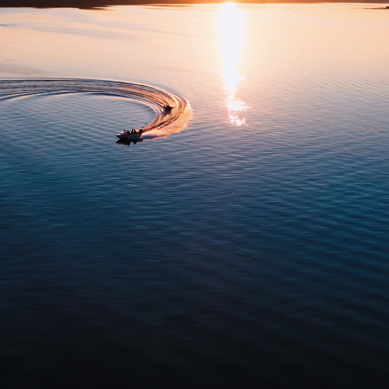 Motion of boats at sunset. Amazing view on the evening river with motor boat leaving paths on water surface. Aerial view.