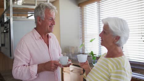 Pareja-Caucásica-Mayor-Hablando-Entre-Sí-Mientras-Toman-Café-Juntos-En-La-Cocina-De-Casa