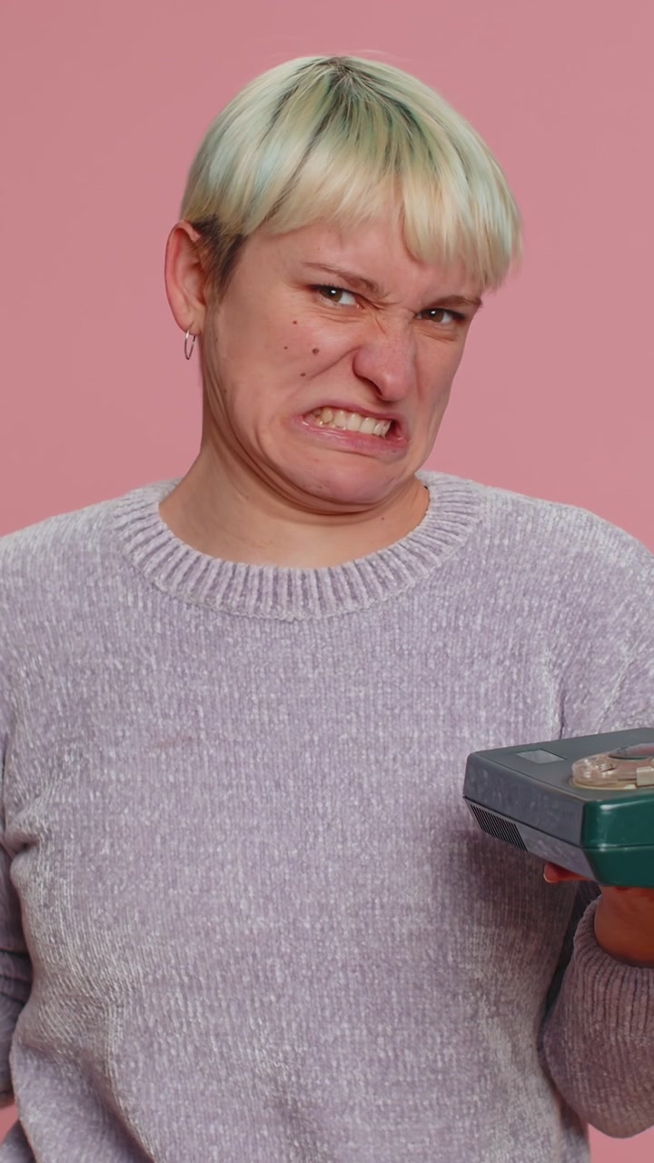 Crazy millennial woman talking on wired vintage telephone of 80s fooling making silly funny faces