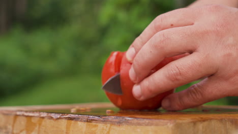 Manos-Masculinas-Cortando-Tomate-Por-La-Mitad-En-Tablero-De-Madera,-Primer-Plano