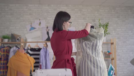 young cute woman fashion designer clothes in glasses working with fabric in studio