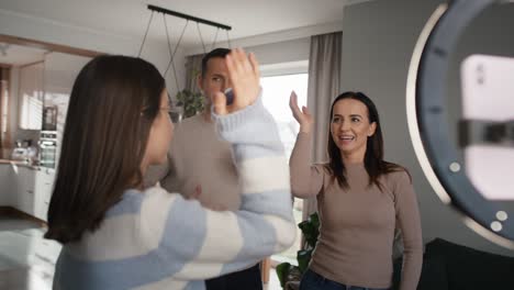 niña adolescente con padres grabando baile para las redes sociales usando teléfono móvil
