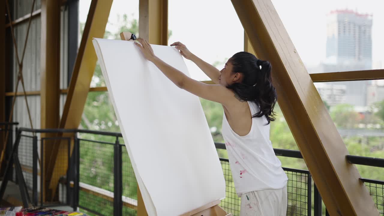 Artist adjusting a blank canvas on an easel