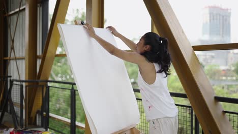 artist adjusting a blank canvas on an easel