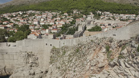 walled old town of dubrovnik croatia with village in the background.