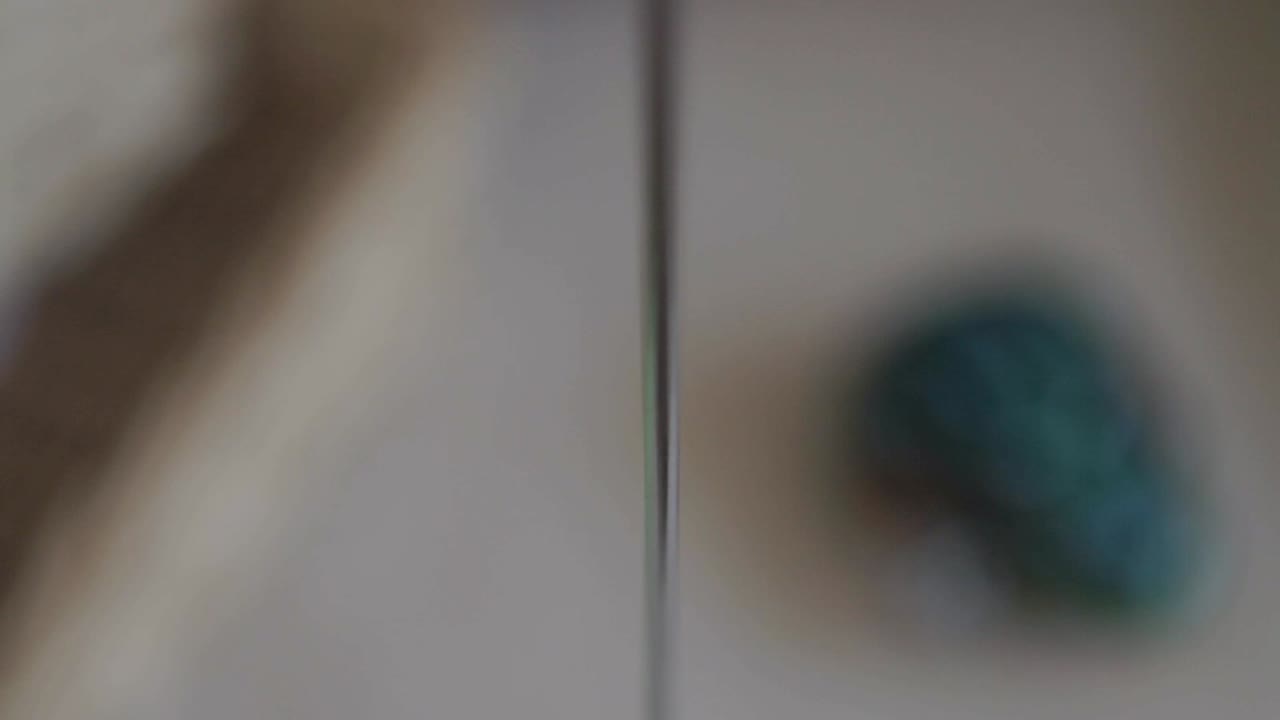 Blurry close-up of a colorful wooden bird toy on a string in motion