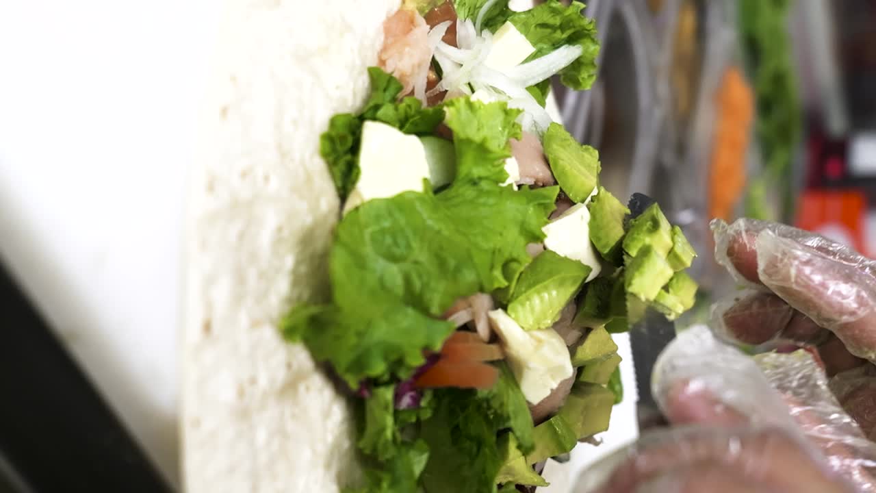 video vertical de un cocinero cortando aguacates mientras prepara un envoltorio saludable