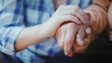 a young woman holds an elderly lady's hand close-up video