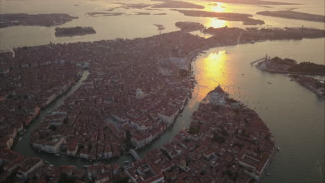 Toma-Aérea-De-Mayor-Altitud-De-Hermosos-Reflejos-De-Luz-Matutina-Sobre-El-Canal-Grande-En-Venecia,-Italia