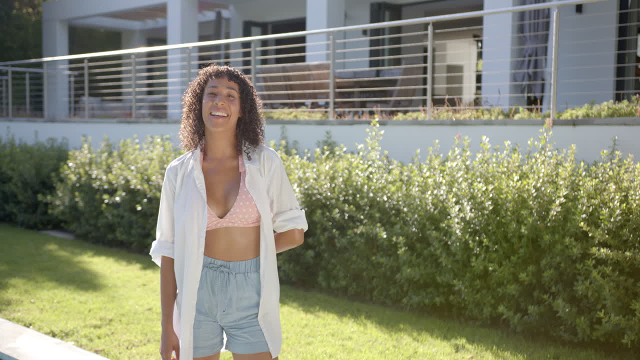Smiling woman in casual summer outfit standing in backyard garden, copy space