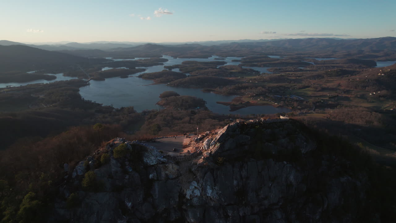 An epic sunset aerial over Bell Knob, a popular tourist hiking location for panoramic views, with a vast landscape of finger lakes around Lake Chatuge in the north Georgia mountains near Hiawassee.