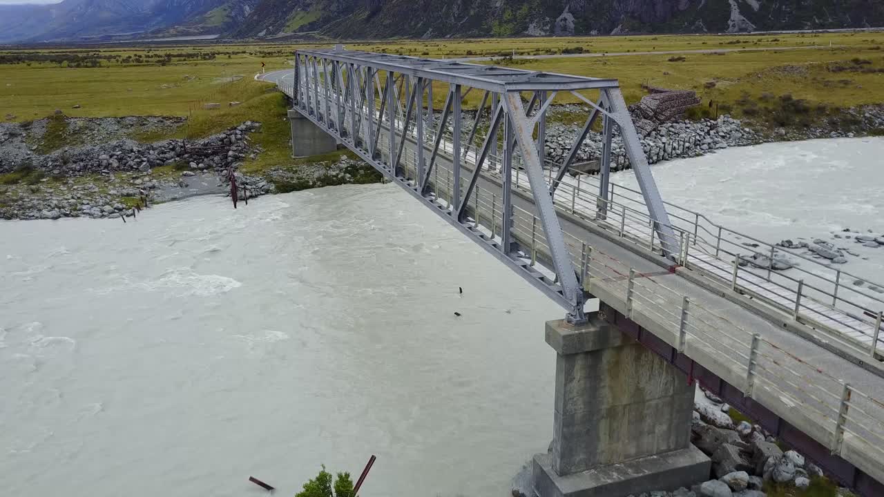 뉴질랜드 마운트 쿡에서 자동차 운전 패스와 함께 산속의 강을 가로지르는 다리의 상승 샷