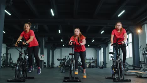 Group-of-girls-performs-aerobic-training-workout-cardio-routine-on-bike-simulators,-cycle-training