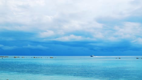 boat sailing across vibrant blue caribbean sea before storm, slow motion pan