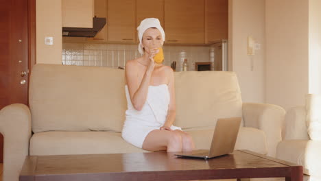 woman relaxing at home with laptop and juice