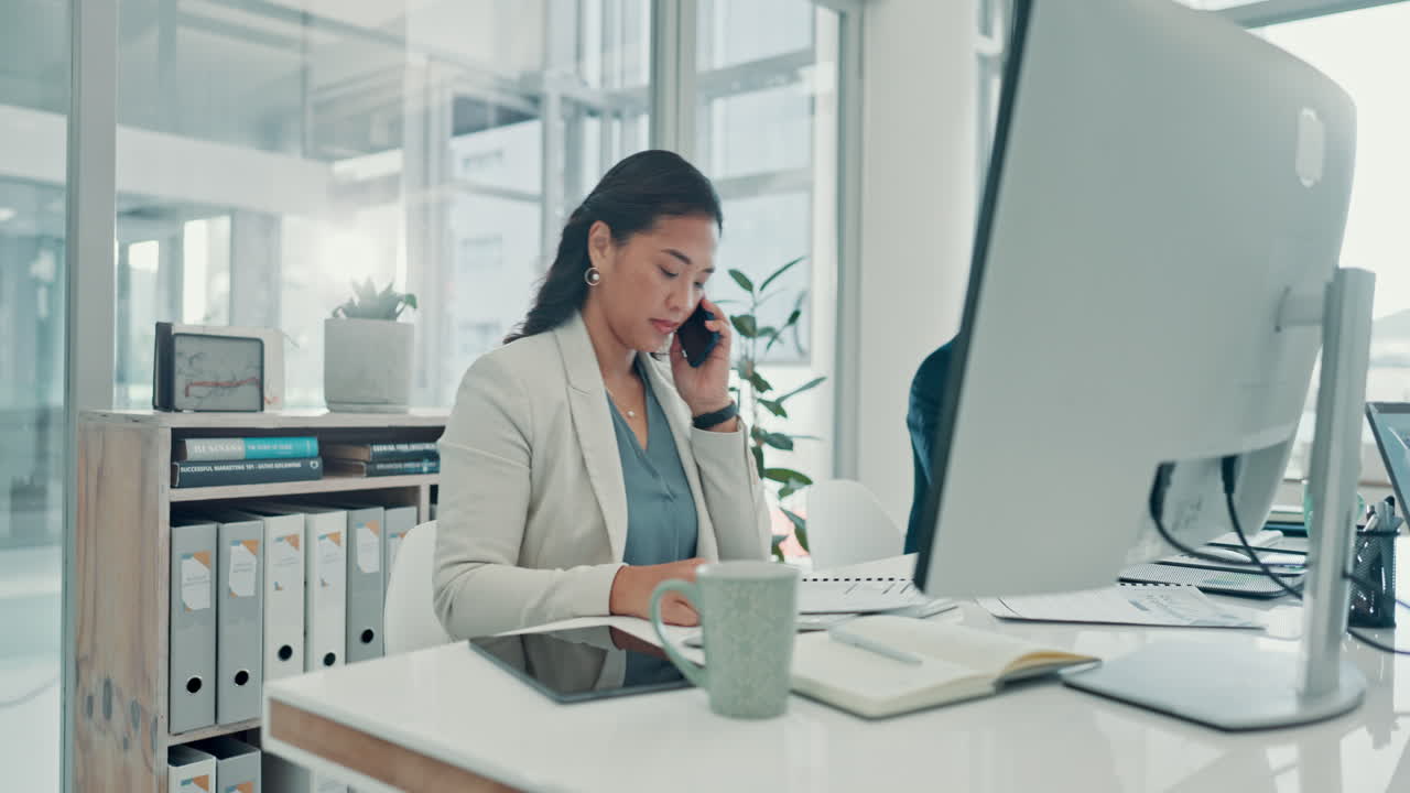 Businesswoman Talking on Phone and Working at Desk in Modern Office