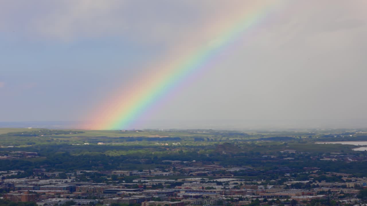 As the sun returns, a radiant rainbow forms over Boulder, shimmering with every color. It’s a peaceful reminder of nature’s wonder.