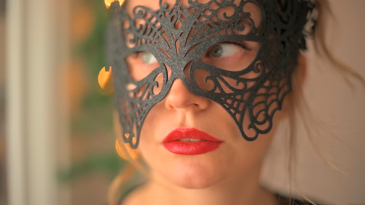 Primo piano di una donna con labbra rosse e occhi azzurri che indossa una maschera nera