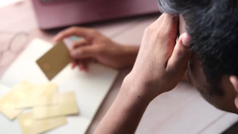 hombre estresado mirando tarjetas de crédito