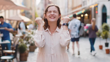 Young woman shouting celebrating success winning goal achievement good victory news in city street