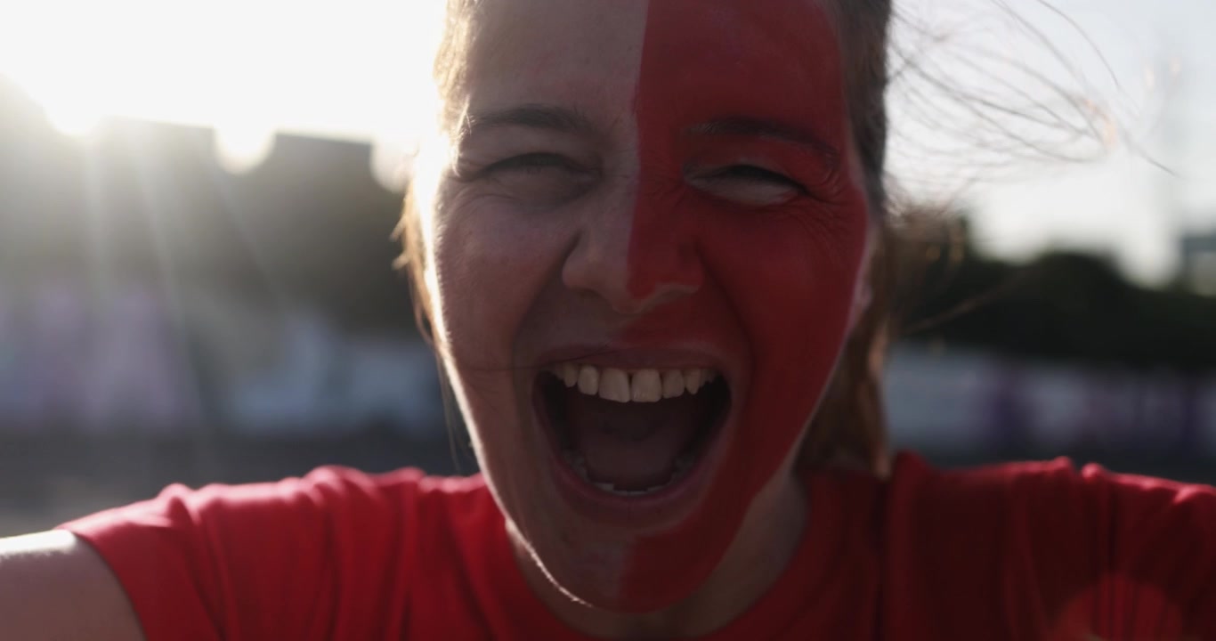 Tifosa con il viso dipinto di rosso e bianco che urla entusiasta