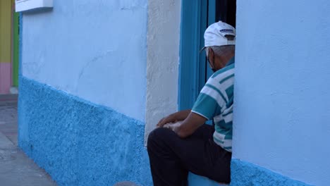 un anciano sentado junto a su casa en esta hermosa isla en guatemala, flores
