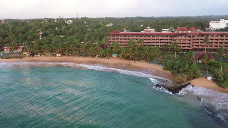 antena descendiendo sobre el océano, la playa y las olas en el popular destino de surf de hikkaduwa en la costa sur de sri lanka