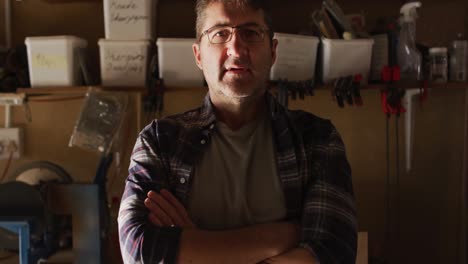 Caucasian-male-knife-maker-in-workshop,-looking-at-camera-and-smiling