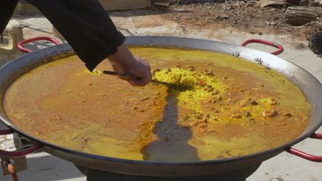 COOK-MOVES-THE-RICE-IN-A-PAELLER-BOWL