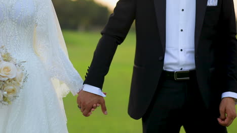 close-up-of-hands-bride-and-groom-holding-at-sunset-in-their-wedding