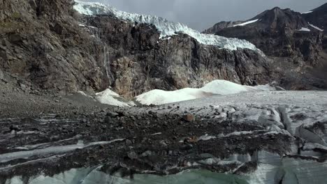gran glaciar en los alpes italianos con cueva, lago verde glacial y roca sobre el hielo, toma aérea de abajo hacia arriba