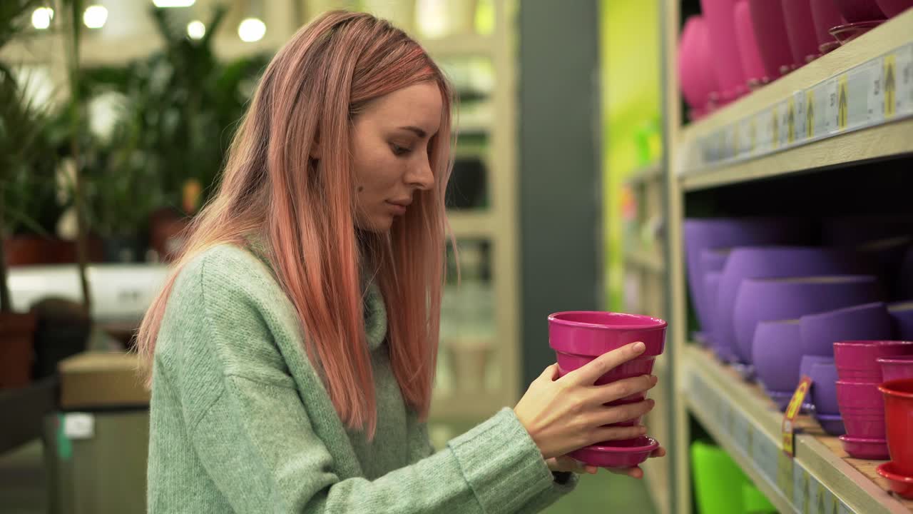 mujer eligiendo macetas coloridas para plantas caseras de los estantes de una floristería