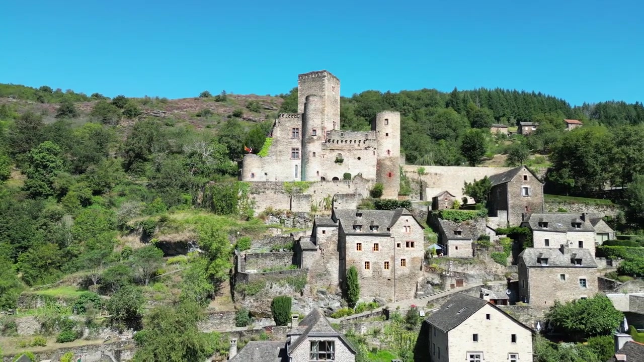 Drone-luftfoto over den franske landsbygda, en liten gammel middelaldersk mursteinsby og et slott på en grønn fjellskog, horisontal panorering på en solrik dag i Belcastel.