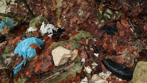 car tyre abandoned in a dry creek, blue plastic garbage pollutes the nature, close up shot