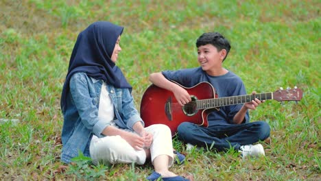 happy asian teenage friends having fun singing and playing guitar