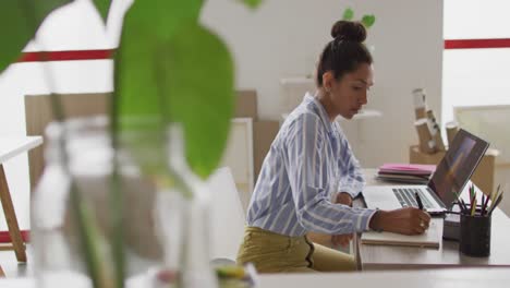Video-of-biracial-female-designer-working-on-laptop-in-studio