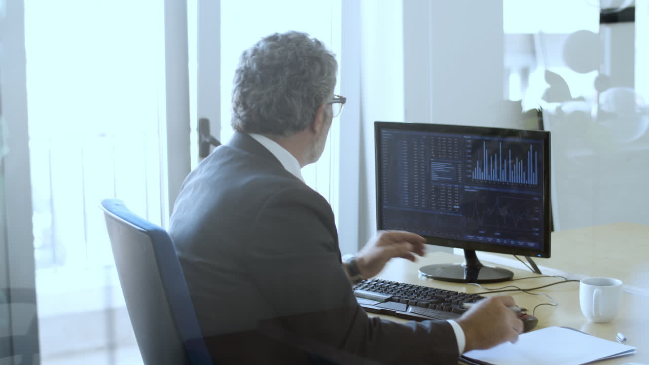 Busy experienced broker sitting and working with the computer