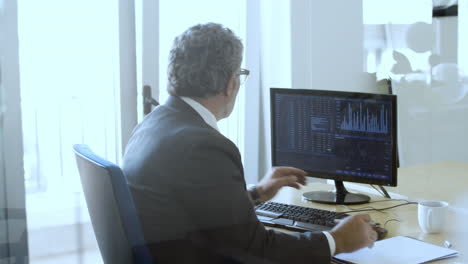 busy experienced broker sitting and working with the computer