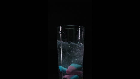 candy falling into fizzy water closeup in slowmotion