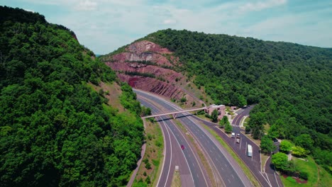 aerial view of highway through mountain pass and forest with rock cut