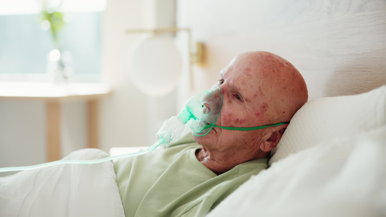 Elderly man with oxygen mask in hospital bed
