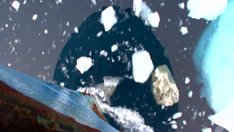 Artistic-shot-looking-straight-down-from-bow-of-ship-to-see-ocean-below-with-icebergs-visible-