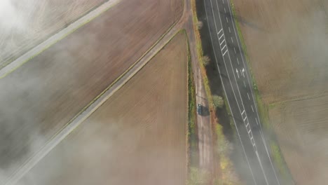 una carretera a través de una zona agrícola rural en luxemburgo, toma de arriba hacia abajo de una mañana con niebla